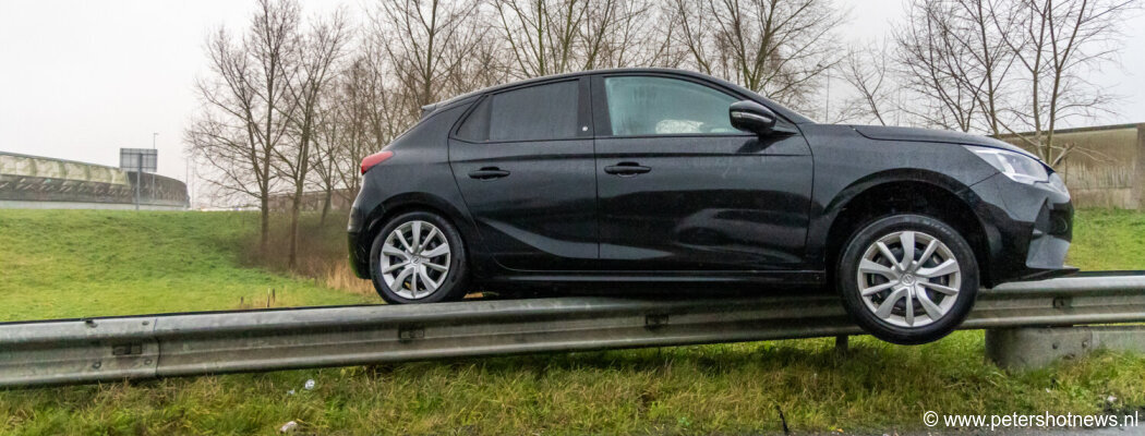 Auto eindigt bovenop vangrail langs snelweg