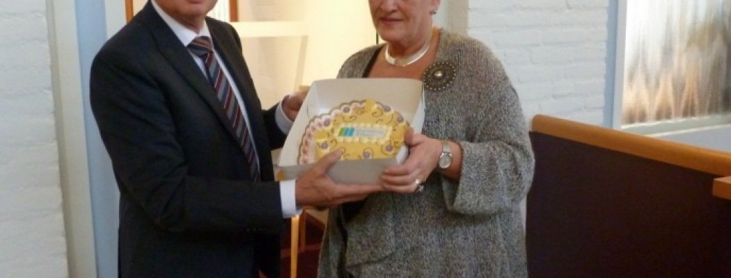 Wethouder Zorg en Welzijn ontvangt een taart met het nieuwe Mantelzorg Steunpunt logo dat wordt Mantelzorg & Meer