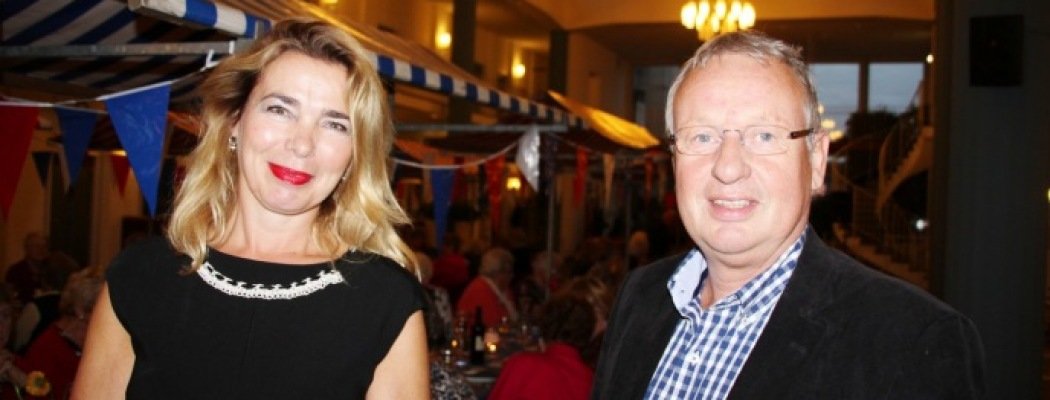 Wethouder Zorg en Welzijn Ad Verburg en Organisator Debby Albers van Thanda met op de achtergrond de mensen aan het diner
